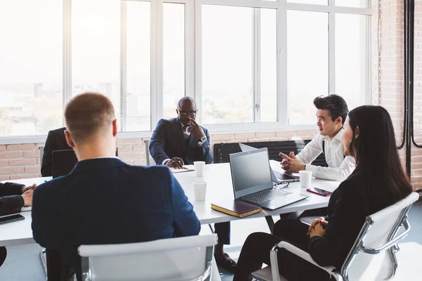 Grupo de jóvenes empresarios que trabajan y se comunican sentados en el escritorio de la oficina junto con sus colegas sentados. reunión de negocios — Foto de Stock