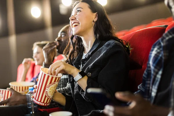 Amigos están viendo una película en el cine con palomitas de maíz. La gente se sienta en los sillones del cine y mira la pantalla — Foto de Stock