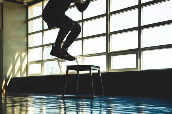 Hombre de los deportes salta en una plataforma especial en el gimnasio frente a la ventana. Crossfit silueta tiro — Foto de Stock