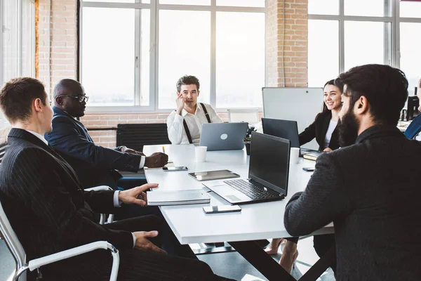 Grupo de jóvenes empresarios que trabajan y se comunican sentados en el escritorio de la oficina junto con sus colegas sentados. reunión de negocios — Foto de Stock