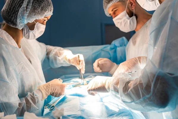 Une équipe internationale de médecins effectue une opération chirurgicale complexe sur un patient sous anesthésie. Une salle d'opération moderne et des chirurgiens expérimentés sauvent des vies — Photo