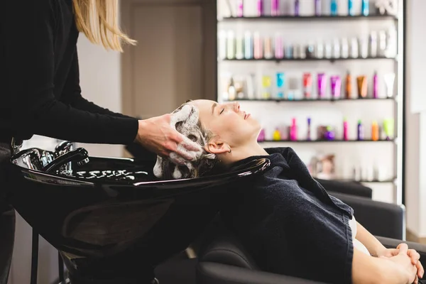 Friseurmeisterin wäscht Haare eines Mädchens mit Shampoo, bevor sie in einem Schönheitssalon stylt. — Stockfoto