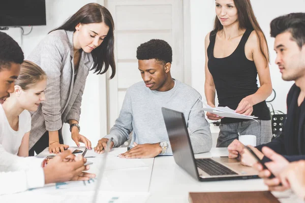 Un equipo de jóvenes trabajadores de oficina, empresarios con portátil trabajando en la mesa, comunicándose juntos en una oficina. Corporativosvapor y gerente en una reunión. coworking. — Foto de Stock