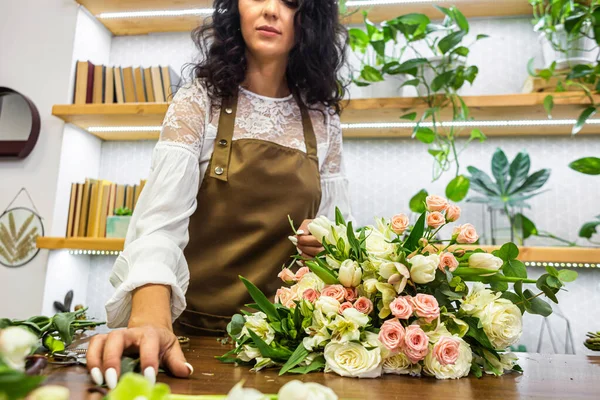 Attractive young woman florist is working in a flower shop