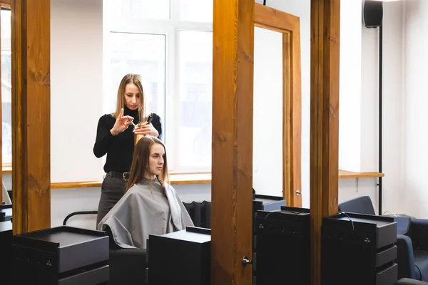 Le maître coiffeur coupe les extrémités des cheveux après le lavage et dans le salon de beauté. — Photo