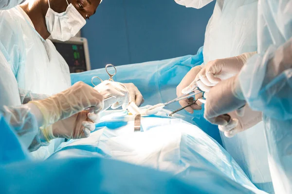 Une équipe internationale de médecins effectue une opération chirurgicale complexe sur un patient sous anesthésie. Une salle d'opération moderne et des chirurgiens expérimentés sauvent des vies — Photo