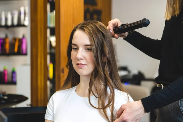 La peluquera maestra riza suavemente a la chica rizadora en un salón de belleza. Peinado del cabello — Foto de Stock