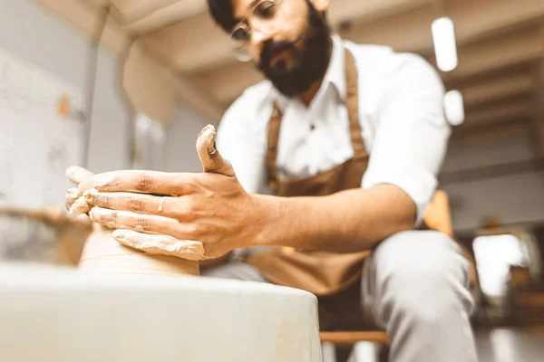 Un jeune potier masculin est engagé dans l'artisanat dans son atelier sur une roue de potiers et fabrique un produit en argile — Photo