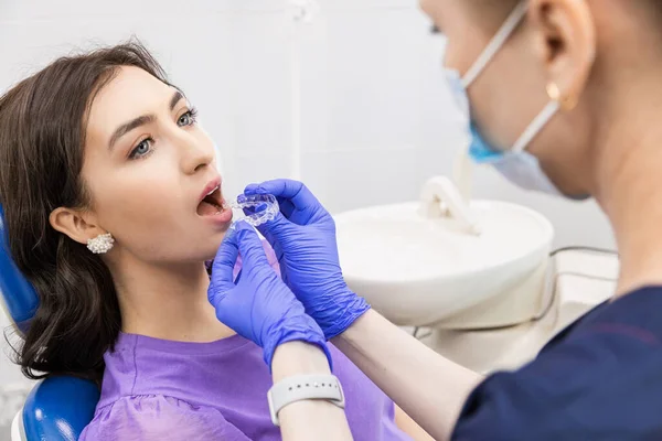 Il concetto di odontoiatria. Servizi odontoiatrici professionali e attrezzature moderne senza dolore. Il medico consulta e tratta la giovane donna, conduce un esame e redige un piano di trattamento. — Foto Stock