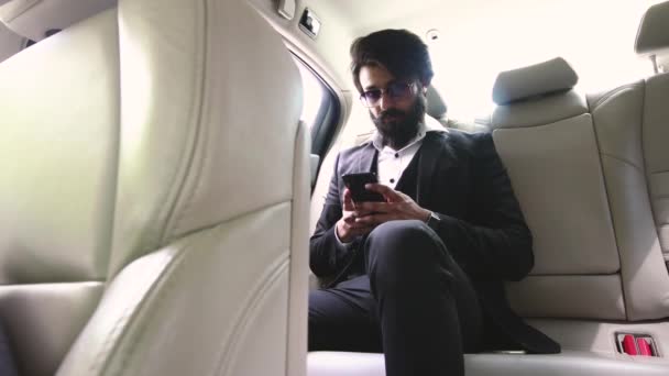 Індуський комерсант з довгою бородою в костюмі і окулярах користується телефоном.. — стокове відео