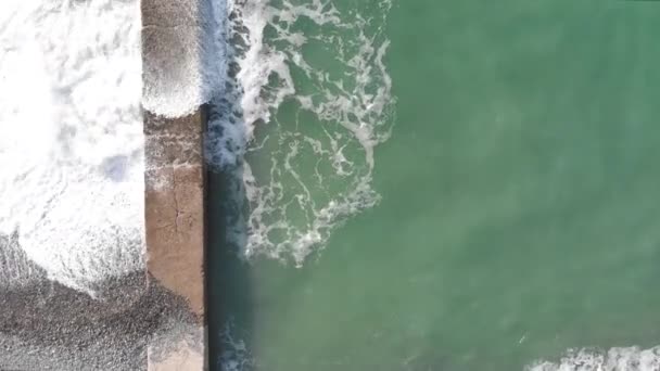 Fotografia aérea de um drone. A voar ao longo da costa. Furo de maré. as ondas colidem contra os quebra-mares — Vídeo de Stock