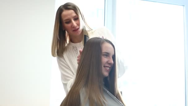Penata rambut menyisir rambut gadis-gadis dengan gaya di salon kecantikan. — Stok Video