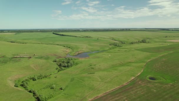 4k Luftaufnahme eines kleinen Sees inmitten landwirtschaftlicher Felder und grüner Wiesen in der Landschaft. Drohnenschießen — Stockvideo