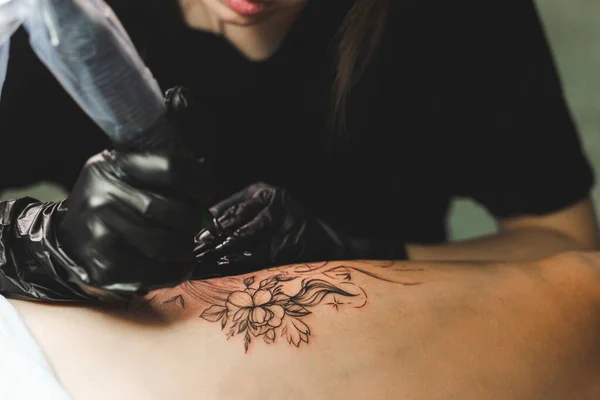 Professional female tattoo artist makes a tattoo in the studio, close-up. Dark photography — Stock Photo, Image