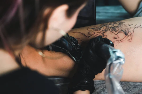 한 여성 이 예술가에게 문신을 새기고, 스튜디오에서 문신을 하고, 몸에 문신을 합니다. 클로즈업 — 스톡 사진