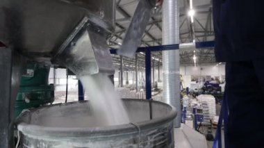 Bir işçi, otomatikman karıştırıcıdan çıkan hammaddeleri fabrikadaki varillere ve poşetlere doldurur. Polipropilen ürünlerinin üretimi