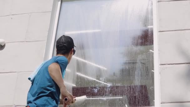 Um trabalhador profissional de uma empresa de limpeza lava as janelas da empresa com produtos químicos especiais — Vídeo de Stock