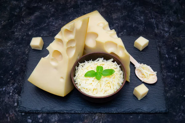 Parça Hollanda Peyniri Siyah Tahta Üzerinde Fesleğen Yapraklı Rendelenmiş Peynir — Stok fotoğraf