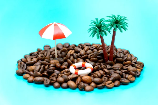 由咖啡豆 棕榈树 海滩伞和蓝绿色背景的救生圈制成的迷你玩具岛 模仿大海 — 图库照片
