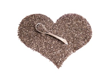 Chia tohumlarından yapılmış bir kalp sembolü ve beyaz arka planda küçük bir çelik kaşık.