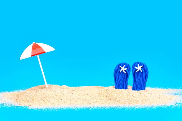 在蓝色的背景下 在沙滩上翻滚着玩具的太阳伞 创意海滩度假概念 — 图库照片