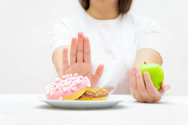 Sıska kız donut yemeyi reddediyor ve kilo vermek ve formda kalmak için taze elma yemeyi seçiyor..