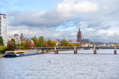 Frankfurt, Germany - October 21, 2025: Frankfurt's comprehensive riverfront perspective features the Main, Eiserner Steg, iconic Cathedral, modern high-rises, and a passenger ship.