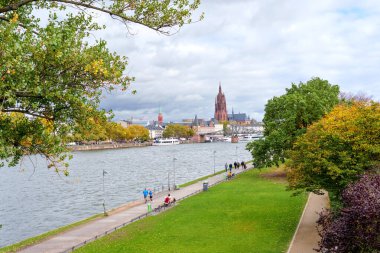 Frankfurt, Almanya - 21 Ekim 2025: Frankfurt 'un Main River seti, tarihi yapılar, yaya altyapısı ve sonbahar parkı içeren birleşik bir şehir manzarası sunar..