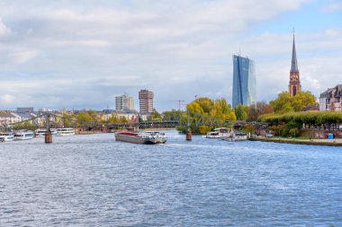 Frankfurt, Germany - October 21, 2025: Expansive view of Frankfurt, Germany's Main River with the Eiserner Steg, ECB tower, and historic cathedral under cloudy skies.