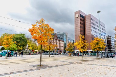 Frankfurt, Germany - October 21, 2025: Frankfurt, Germany, urban square showcases autumn foliage, modern corporate architecture, historic buildings, public transport infrastructure, and pedestrians.
