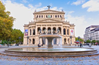 Frankfurt, Almanya - 21 Ekim 2025: Frankfurt 'un ikonik Alte Oper' inin geniş açı görüntüsü, şehir merkezindeki sonbahar yeşilliklerinin ortasındaki klasik bir çeşmenin arkasında görkemli bir şekilde yükseliyor..