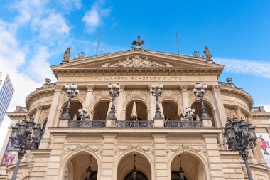 Frankfurt, Almanya - 21 Ekim 2025: Neoklasik görünüşüyle, heykeller ve dekoratif detaylarla süslenmiş, berrak mavi gökyüzü altında parıldayan ikonik Alte Oper binasının alçak açılı görüntüsü.