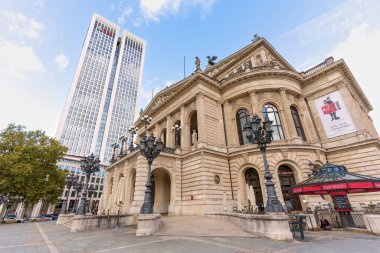 Frankfurt, Almanya - 21 Ekim 2025: Eski Opera binasının geniş açılı perspektifi, Frankfurt 'ta güneşli bir sonbahar gününde mavi gökdelen altında modern bir gökdelene karşı kurulmuştur..