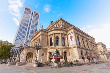 Frankfurt, Almanya - 21 Ekim 2025: Frankfurt 'un ikonik Alte Oper' i açık mavi gökyüzü altında modern bir gökdelene karşı duruyor. Açık hava kahvesi şehir manzarasını güzelleştiriyor..