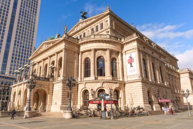 Frankfurt, Germany - October 21, 2025: Frankfurt's grand Alte Oper building features ornate architecture and an outdoor cafe, contrasting with modern city life under a blue sky in Germany.