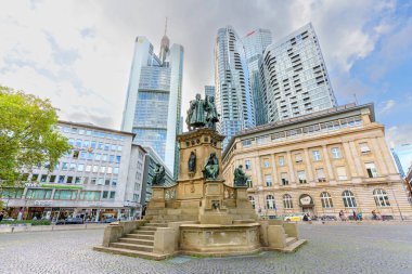 Frankfurt, Almanya - 21 Ekim 2025: Gutenberg Anıtı Frankfurt 'un şehir merkezinde, parlak, bulutlu bir gökyüzü altında tarihi ve modern gökdelenlerin bir karışımı ile çevrelenmiştir.