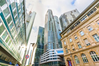 Frankfurt, Almanya - 21 Ekim 2025: Frankfurt 'un kentsel manzarasında modern cam gökdelenler parlak bir gökyüzü altında klasik taş bir binayla yan yana geldi..