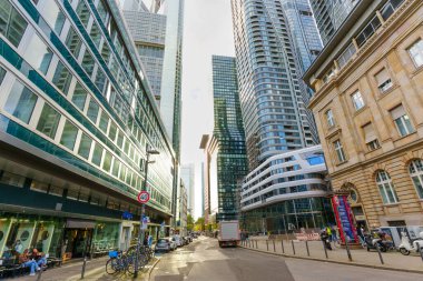 Frankfurt, Almanya - 21 Ekim 2025: Frankfurt 'un canlı şehir merkezi sokak gösterileri modern cam gökdelenler, tarihi bir taş bina ve parlak bir günde park edilmiş araçlar.