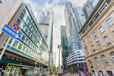 Frankfurt, Almanya - 21 Ekim 2025: Frankfurt 'un hareketli şehir caddeleri modern cam gökdelenler ve bulutlu gökyüzü altında araçlar ve yayalarla klasik bir taş bina karışımı sergiliyor