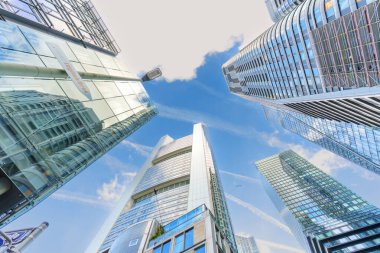 Frankfurt, Almanya - 21 Ekim 2025: Frankfurt 'un modern kentsel manzarasını vurgulayan yansıtıcı cepheli cam ve çelik gökdelenlerin dinamik düşük açılı perspektifi.