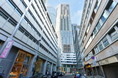 Frankfurt, Almanya - 21 Ekim 2025: Güneşli bir günde park halindeki araba ve yayalarla dolu işlek caddelerin üzerinde yükselen şık çağdaş gökdelenlerin yer aldığı etkileyici kentsel manzara.