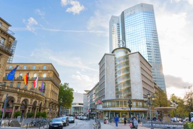 Frankfurt, Almanya - 21 Ekim 2025: Frankfurt 'un kentsel caddesi, açık bir günde açık mavi gökyüzünün altında bayrakları bulunan modern cam gökdelen ve tarihi Steigenberger Oteli' ne sahiptir..