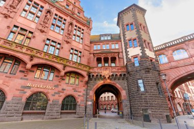 Frankfurt, Almanya - 21 Ekim 2025: Tarihi kırmızı kumtaşı Alte Brcke, berrak mavi gökyüzüne karşı güzelliği yansıtan sakin ana nehrin üzerinde görkemli bir şekilde kemer sallıyor