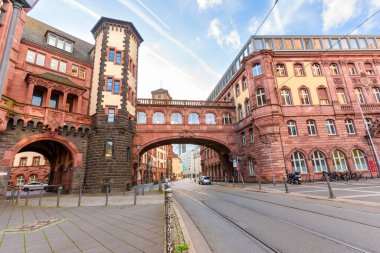 Frankfurt, Almanya - 21 Ekim 2025: Tarihi kırmızı kumtaşı Alte Brcke, berrak mavi gökyüzüne karşı güzelliği yansıtan sakin ana nehrin üzerinde görkemli bir şekilde kemer sallıyor