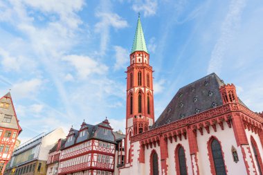 Frankfurt, Almanya - 21 Ekim 2025: Frankfurt Katedrali 'nin kırmızı kumtaşı kuleleri parlak mavi gökyüzü altındaki geleneksel yarı keresteli evlerin üzerinde.