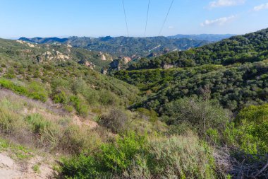 Geniş manzara, Santa Monica Dağları 'ndaki kırmızı kaya kanyonu parkının engebeli, yemyeşil tepelerini ve dramatik kanyonlarını gözler önüne seriyor..