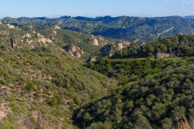 Yoğun yeşil şapellerle kaplı yuvarlanan tepeler, çarpıcı kırmızı kaya oluşumlarıyla kaplı, Red Rock Kanyon Parkı 'nın geniş ve sakin manzarasını tanımlıyor..