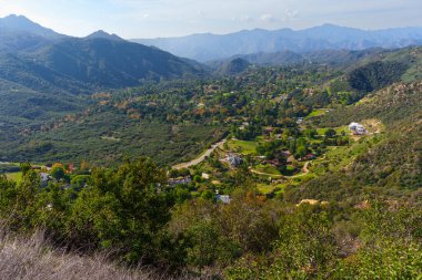 Geniş panoramik manzara, yerleşim yerleri, virajlı yollar ve uzak Santa Monica Dağları 'na uzanan yoğun şapelin yer aldığı Red Rock Canyon Park vadisini ayrıntılarıyla anlatıyor..