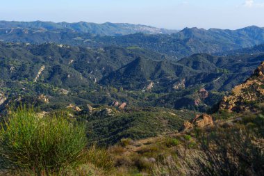Geniş açılı geniş manzara, yuvarlanan yeşil dağları ve engebeli Kızıl Kaya Kanyon Parkı 'nı parlak mavi gökyüzünün altında görüntüler, uzak tepeleri gözler önüne serer..