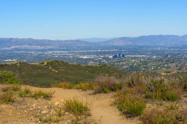 Kırmızı Kaya Kanyon Parkı, Santa Monica Dağları 'ndaki engebeli çalılıklarda gezinen toprak yürüyüş yolları geniş şehir genişliği ve uzak puslu dağların panoramik manzarasını sunuyor..